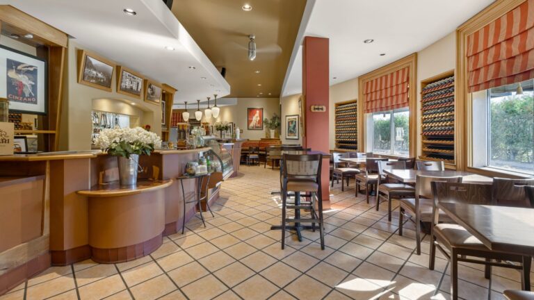 Italian-style hotel restaurant interior featuring dining tables and tiled flooring.